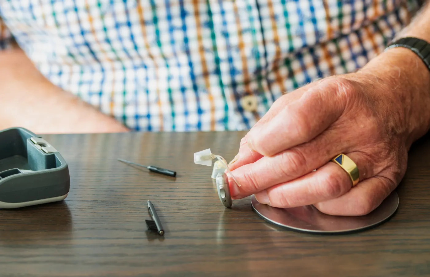 Person cleaning a hearing aid with a brush